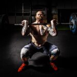 Man in Black Shorts Carrying Adjustable Barbells