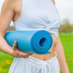 Woman Standing and Holding Blue Yoga Mat