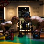 a man and a woman doing push ups with kettles